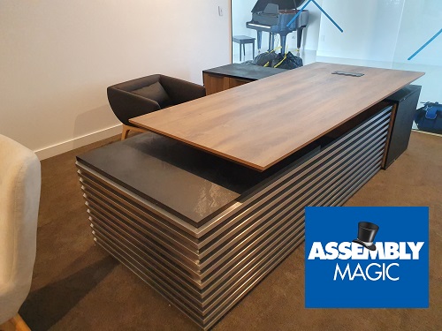 A premium office desk with Assembly Magic logo in bottom right corner