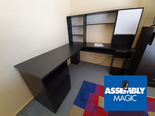 Large corner desk with Assembly Magic logo in bottom right corner